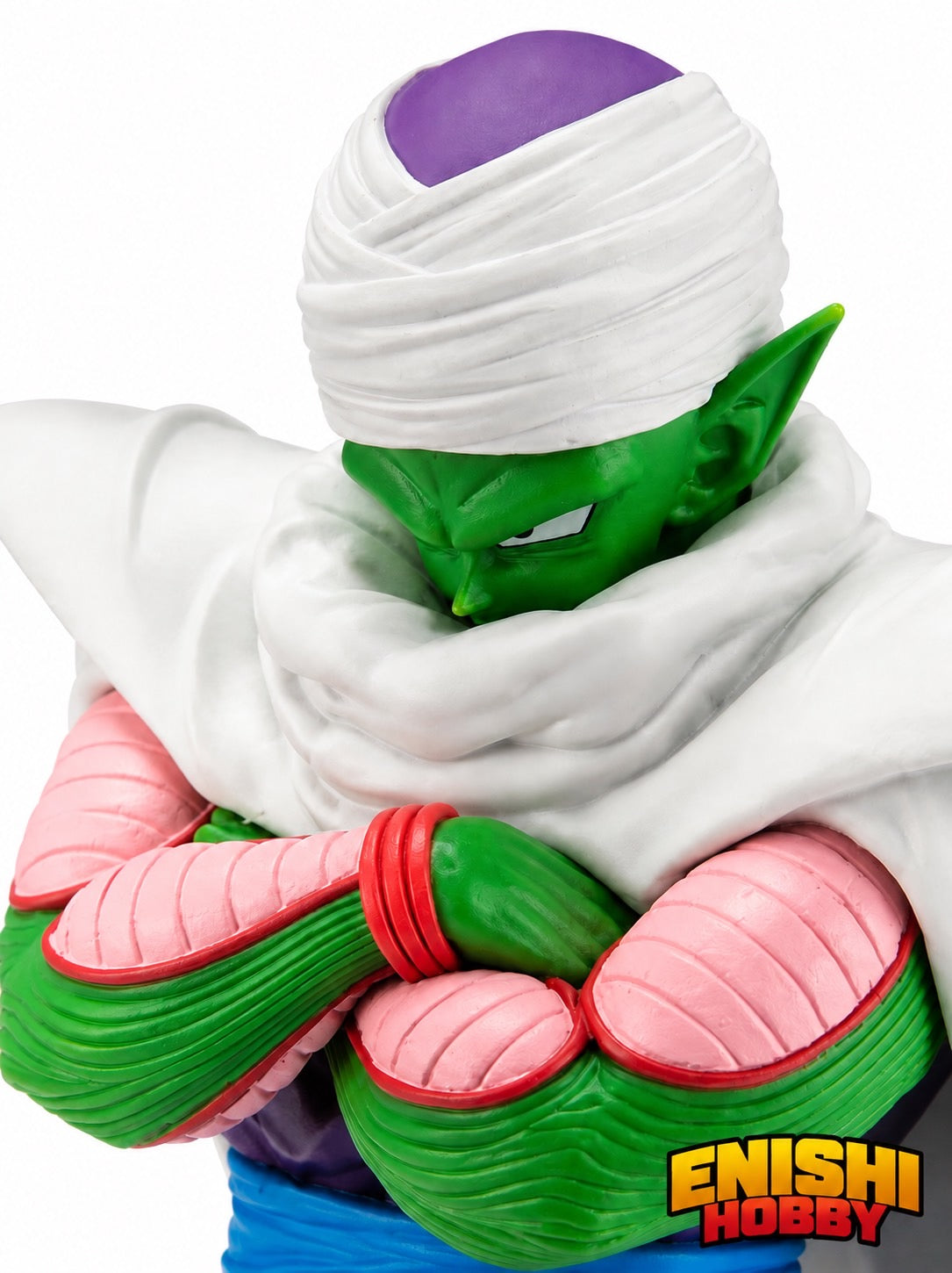 Close-up detail shot of the Piccolo figure showing the intricately sculpted face, white turban, and crossed arms with green forearms and pink elbow pads.
